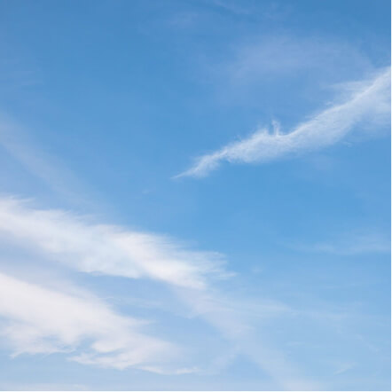 Clear replacement window glass showing an unobstructed view of a bright blue sky with soft white clouds. The transparent glass allows maximum natural light and visibility while maintaining a clean modern appearance for residential windows.