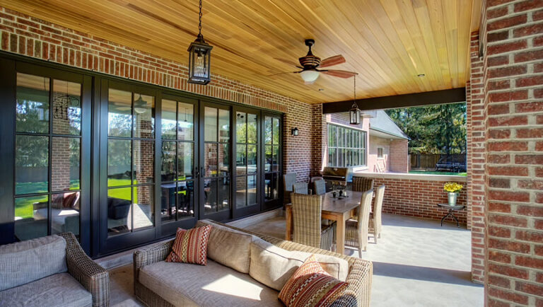 Custom black-frame folding patio doors and a large architectural window opening up to a luxury covered patio.